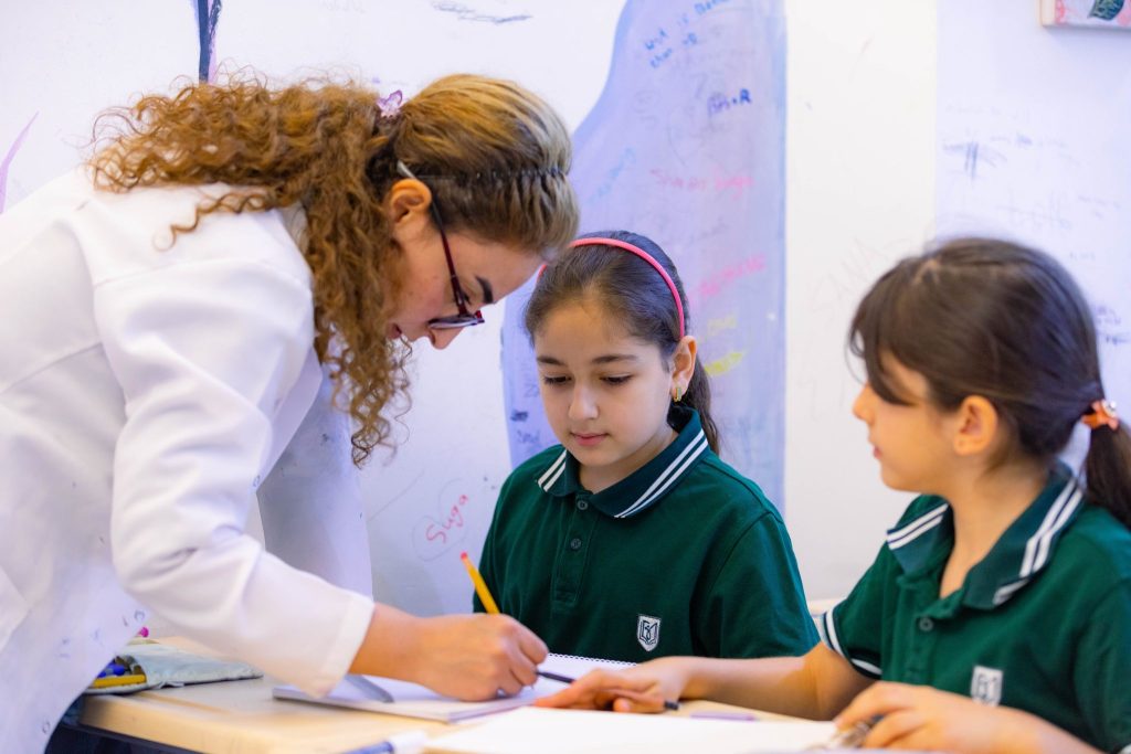 Teacher assisting primary school girls with classroom task